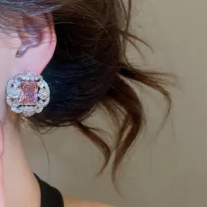 Close-up of elegant earring with a square pink zircon and crystal-set lace border.