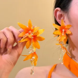 Detailed view of elegant orange floral tassel earrings with pearls and crystals