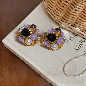 Detail view of vintage palace style stud earrings with purple flowers and pearl.
