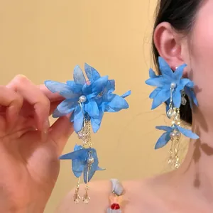 Detail view of blue fabric flower earrings with elegant pearl and crystal tassels