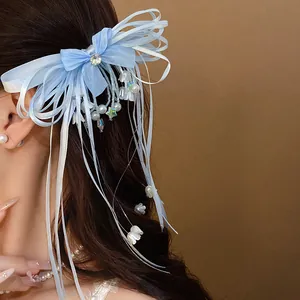 Elegant blue ribbon bow hair clip with tassels, pearls and rhinestone detail on long hair