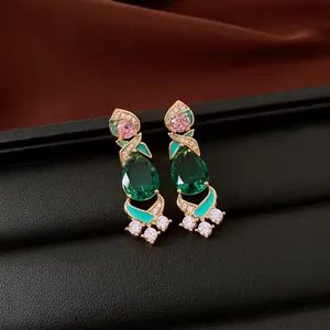 Detailed view of vintage-style emerald green and pink zircon earrings with gold plating.