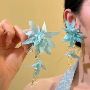 Detailed macro view showing light blue fabric flower tassel earrings with pearls decoration