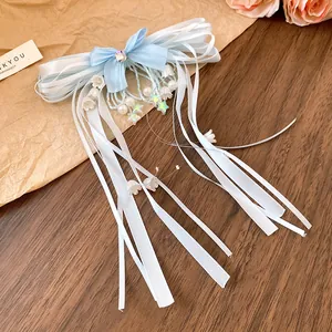 Detail view of light blue ribbon bow hair clip with white lily tassels and pearls.