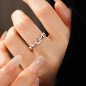 Detailed close-up view of a silver open ring with a circular resin stone on a finger