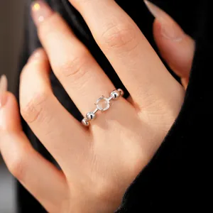 Close-up detail of a minimalist silver open ring with a round clear stone on the finger