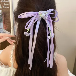 Detail of purple satin ribbon bow hair clip with pearl and floral accents on hair