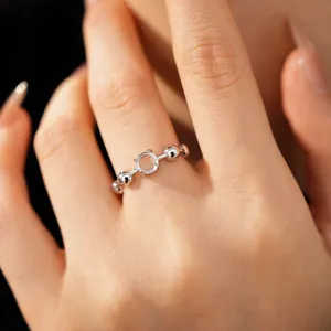 Detailed close-up of a silver open ring with a central circular zircon and beads