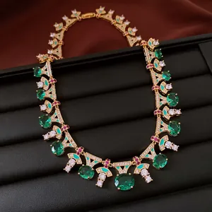 Close-up of vintage gold-plated necklace with green zircons and geometric details.