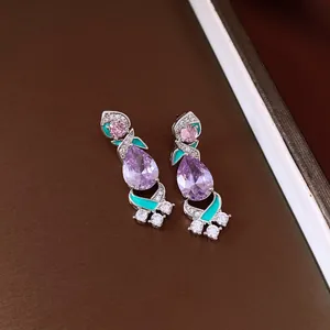 Close-up of vintage purple teardrop zircon earrings with green enamel detail