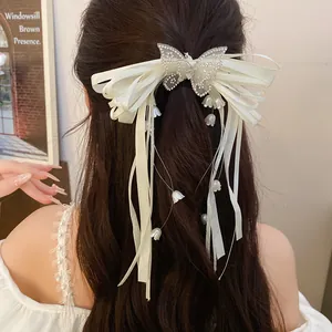 Back view of elegant white satin bow hair clip with rhinestone butterfly and lily of the valley