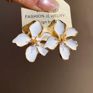 Close-up detail of elegant white enamel flower earrings with gold trim