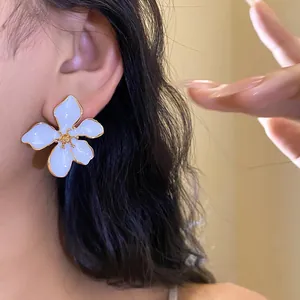Close-up of light blue enamel flower earrings on ear showing elegant petal detail