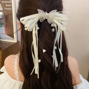 Macro view of white ribbon hair clip featuring rhinestone butterfly and lily tassels