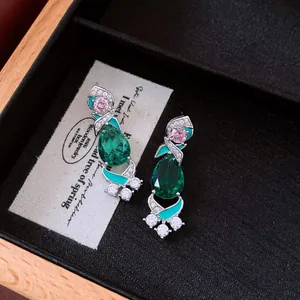 Detailed view of vintage-style earrings featuring emerald green stones and pink zircons