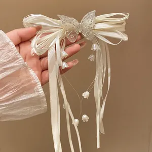Close-up of rhinestone butterfly and lily of the valley tassels on ribbon bow hair clip.