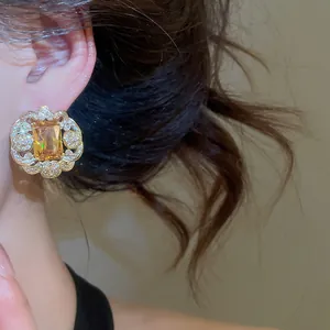 Close-up of sparkling rectangular yellow zircon earrings with crystal-encrusted lace border