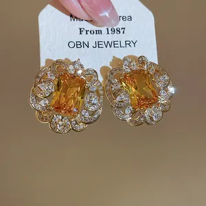 Close-up of luxury square yellow zircon stud earrings with intricate gold filigree