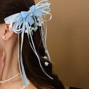 Detail of light blue ribbon bow hair clip with tassel and lily of the valley charms