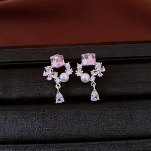 Macro detail of zircon earrings with pink crystal and white pearl in a drop design