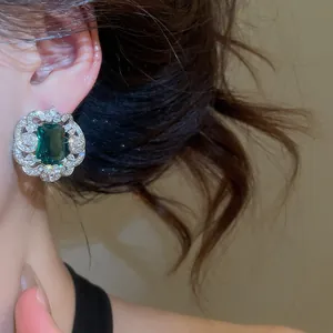 Close-up of a luxury emerald green square stud earring with sparkling crystal lace border