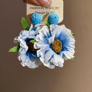 Handmade blue fabric flower drop earrings featuring raffia accents and silver needle studs