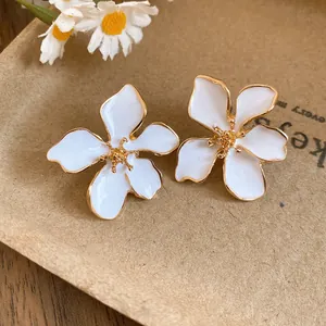 Close-up detail of elegant white enamel flower stud earrings with golden edges.