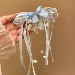 Close-up of a blue ribbon bow hair clip with lily of the valley tassels and rhinestones.