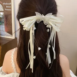 Close-up of elegant cream satin bow hair clip with sparkling rhinestone butterfly