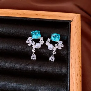 Close-up of zircon pearl earrings with blue cube crystals and teardrop dangle