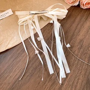 Detail of white ribbon bow hair clip with lily of the valley tassels and silver clip