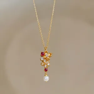 Nahaufnahme einer vergoldeten Vintage-Halskette mit Zirkonia-Blume und Perlenanhänger