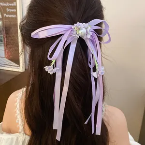 Close-up of purple ribbon bow hair clip with pearl and floral tassel details