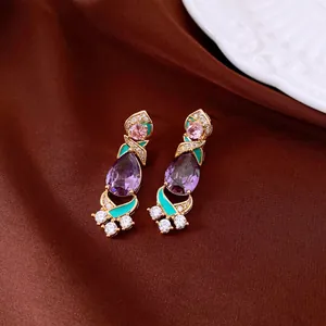 Close-up of vintage earrings with purple pear crystals and teal enamel detail