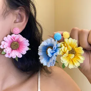 Close-up detail of oversized colorful fabric flower drop earrings with silver needles.