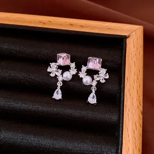 Detailed view of elegant silver needle earrings with pink crystal and pearl drop