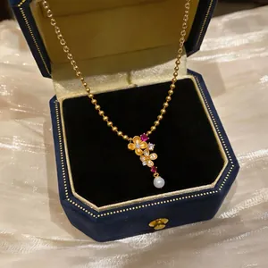 Nahaufnahme einer goldenen Vintage-Blumenkette mit Zirkonia und Perle in blauer Samtbox