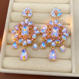 Close-up detail of ornate palace style earrings featuring iridescent purple crystals in a gold setting