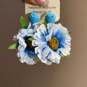 Detailed view of handmade blue raffia fabric flower stud earrings on display card