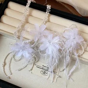 Detailed close-up of elegant white feather and flower jewelry set in a premium display box