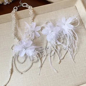 Detailed view of delicate feather flower and pearl bridal jewelry set on a tray