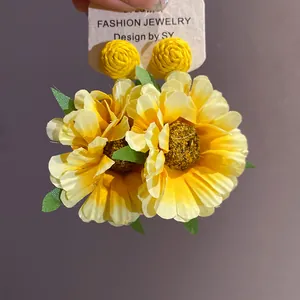 Detailed macro view of handmade yellow sunflower raffia fabric flower stud earrings