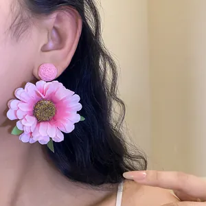 Detailed view of pink raffia fabric flower earrings worn by a model in natural light.