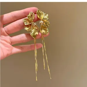 Detail view of gold-tone floral stud earrings with cascading tassels and crystals