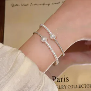 Close-up detail of elegant white pearl and sparkling crystal beaded bracelets on a wrist.