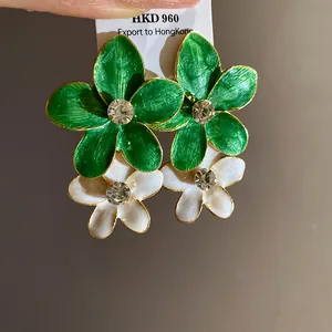 Detail of green and white enamel flower earrings with central rhinestone accents