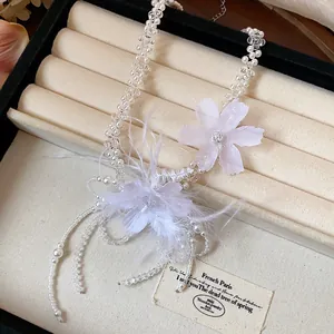 Detailed view of ethereal white pearl necklace with delicate fabric flowers and feathers