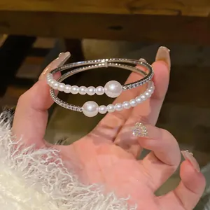 Close-up of elegant silver-tone bangles featuring lustrous pearls and sparkling crystals