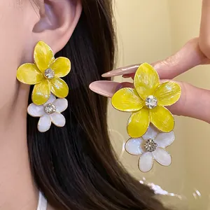 Close-up of yellow and white enamel flower earrings with sparkling rhinestones