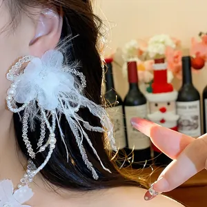 Detailed view of elegant white feather and pearl flower drop earring on model.